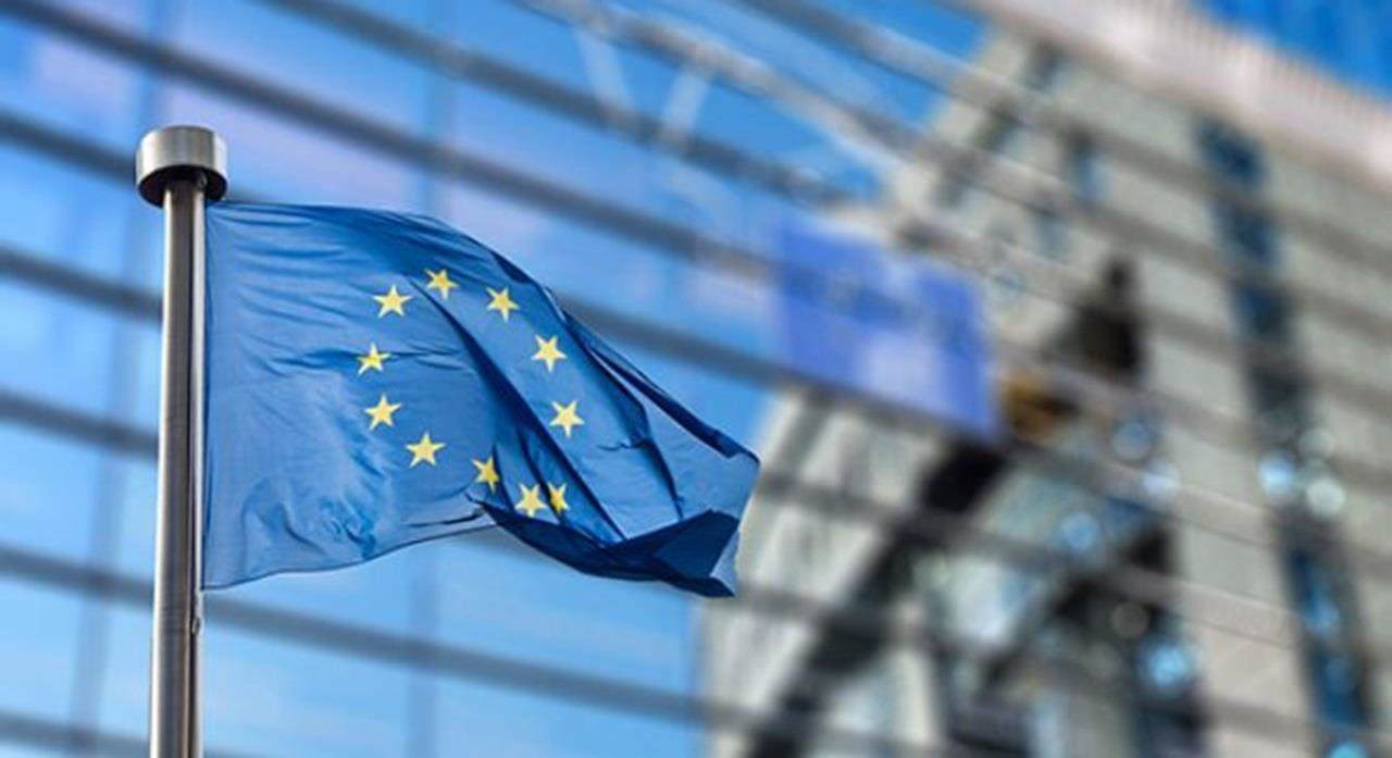 European Union Flag againts a background of a glass building facade
